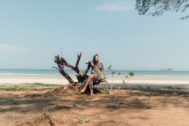 De vrouw ontspant op het strand onder de pijnboomboom in kalme atmosfeer.