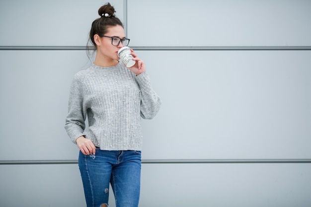 De vrouw op de achtergrond van grijze muren met lang zwart haar en een bril voor zicht