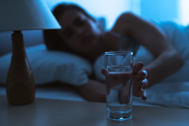 De vrouw op het bed met een alcoholshot