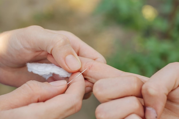 De vrouw probeert de splinter uit de hand van het kind te trekken Een splinter in de hand van een kind