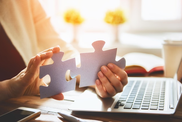 De vrouw probeert het stuk van het paarpuzzelstuk te verbinden. Symbool van associatie en verbinding. Concept van bedrijfsstrategie.