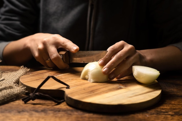 De vrouw snijdt een ui op een houten close-up als achtergrond Voorbereiding voor het koken