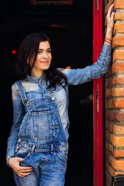 De vrouw staat bij de deur van het gebouw en houdt haar hand tegen de muur