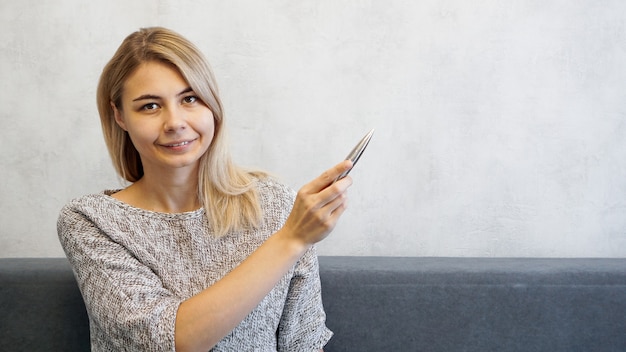 De vrouw toont met een pen op een grijze muur