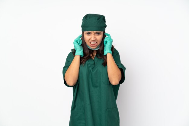 De vrouw van de chirurg in groen uniform die op witte muur wordt gefrustreerd en oren behandelt