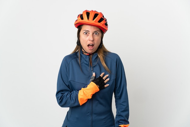 De vrouw van de middelbare leeftijdsfietser die op witte muur wordt geïsoleerd die verrast en geschokt terwijl naar rechts kijkt