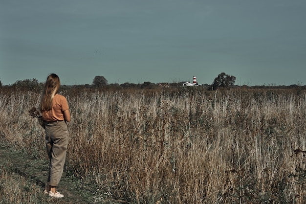 De vrouw verzamelt bloemen in het veld. Biologisch afbreekbare tas.