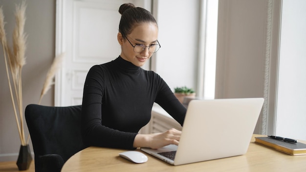 De vrouw werkt met een bril gebruikt een laptop schrijft een antwoordbericht per post aan de klant Bedrijfsrapport