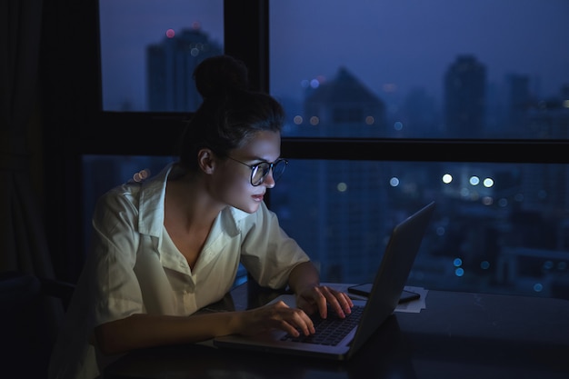 De vrouw werkt thuis met laptop tijdens nacht.