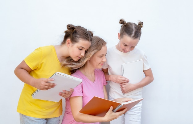 De vrouw wijst in een notitieboekje en legt de kinderen uit.