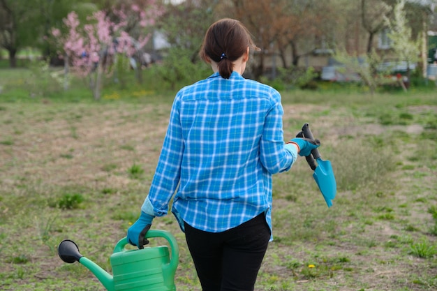 De vrouwelijke gieter van de tuinmanholding en tuingereedschap