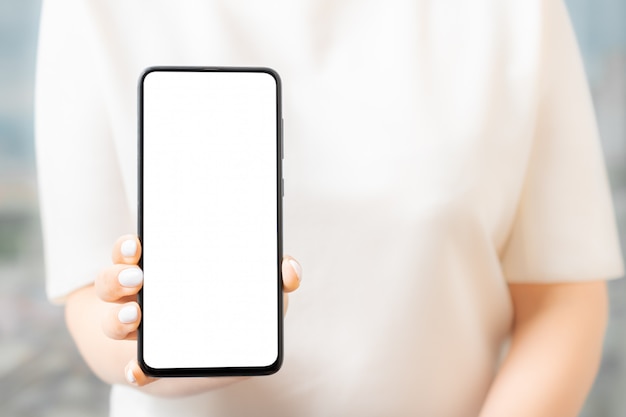 De vrouwelijke hand houdt de slimme telefoon met het lege ruimte scherm voor uw tekstbericht of informatie-inhoud, mockup