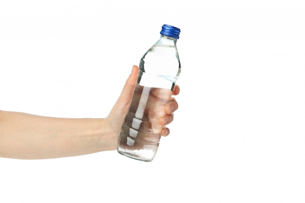 De vrouwelijke hand houdt fles met water, dat op wit wordt geïsoleerd