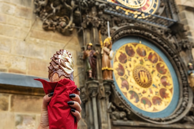 De vrouwelijke hand houdt traditionele tsjechische koekjestrdelnik op scène van astronomische klok in de stad van praag