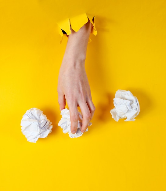 De vrouwelijke hand houdt verfrommelde ballen van document door gescheurd geel document. minimalistisch idee bedrijfsconcept