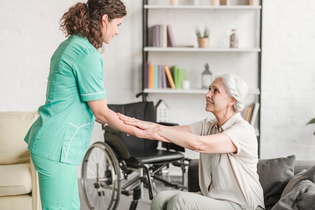 Foto de vrouwelijke handen van de verpleegstersholding van hogere gehandicapte vrouw