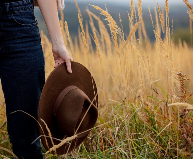 De vrouwelijke hoed van de handholding over geel gras bij platteland