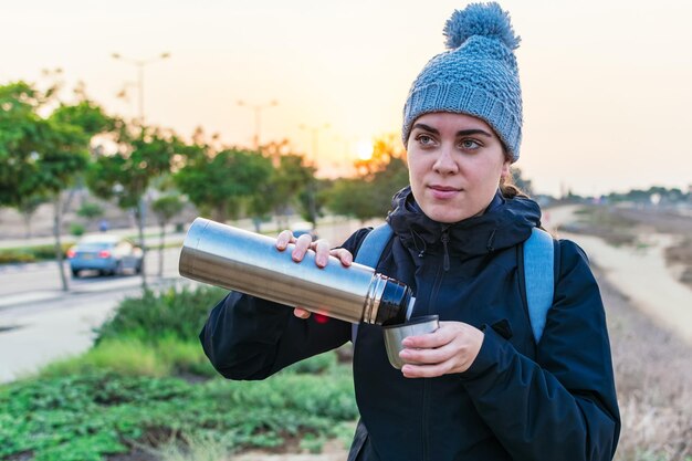 De vrouwelijke wandelaar drinkt een kop warme koffie Winter avontuur