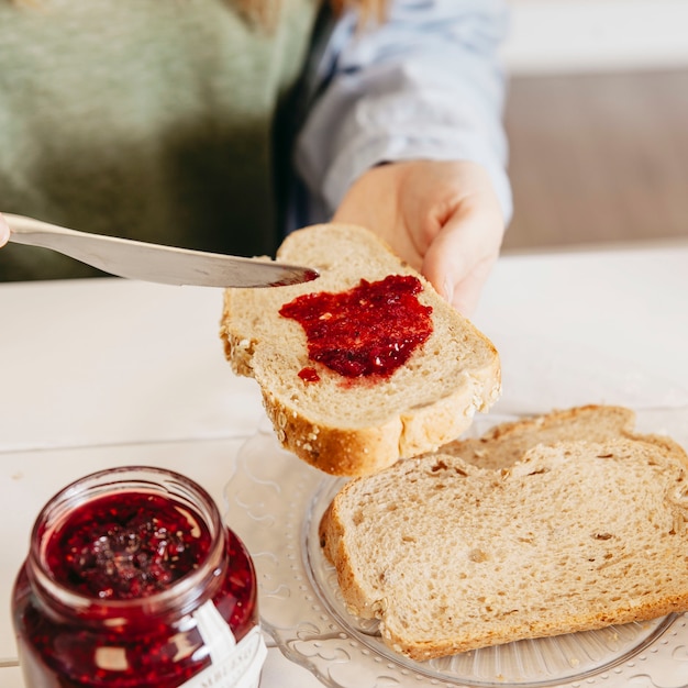 De vrouwen versmerende jam van de close-up op brood