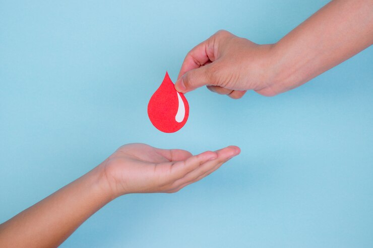 De vrouwenhand geeft een rode bloeddaling aan een jongenshand voor bloeddonatieconcept, de dag van de Wereldbloedgever.
