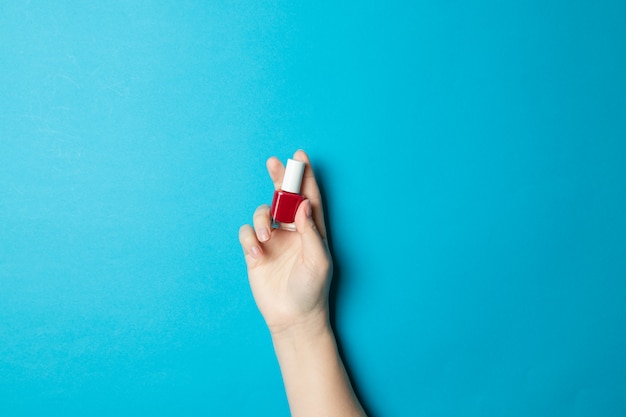 De vrouwenhand houdt een glasmanicure een fles met rode vernis