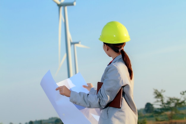 de vrouweningenieur die van portretvrouwen en blauwdrukken werken houden bij windturbinelandbouwbedrijf