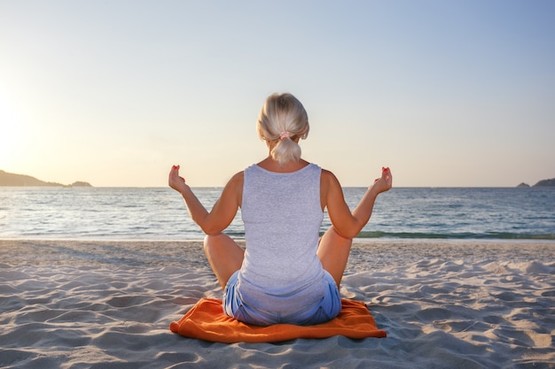 De vrouwenmeditatie in een yoga stelt bij het strand.