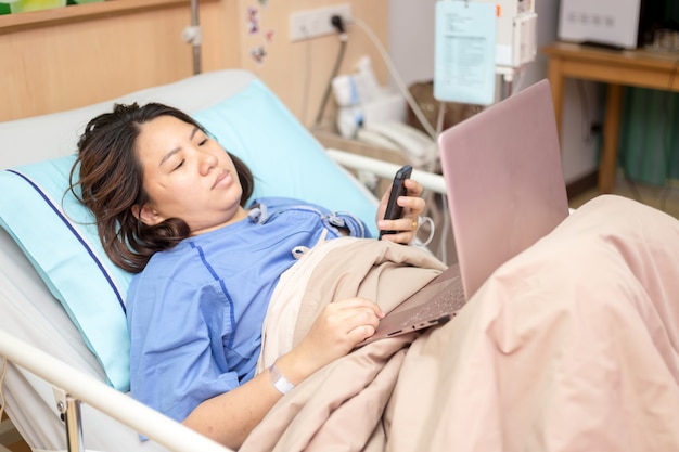 De vrouwenpatiënt die van Azië met laptop tijdens in het ziekenhuis werken