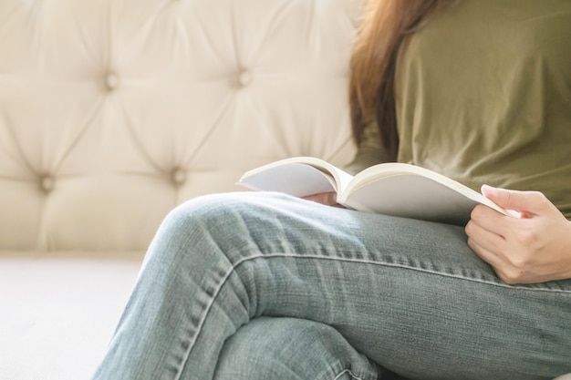 De vrouwenzitting van de close-up op bank voor het lezen van een boek in vrije tijd in de middag