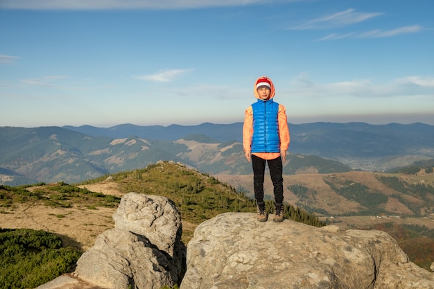 De wandelaar van de jonge kindjongen die zich in bergen bevindt die van mening van verbazend berglandschap genieten.