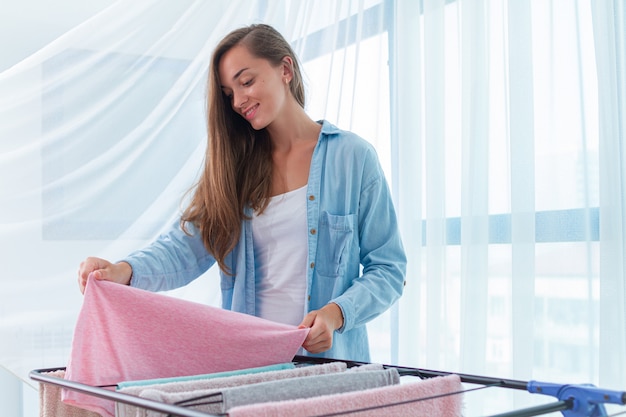 De wasvrouw hangt schone natte doek op wasdroger na thuis wassen. huishoudelijke taken en huishouden