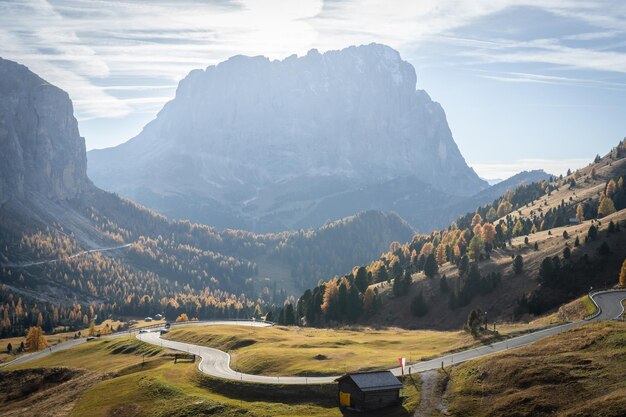 Foto de weg bocht in een hoge alpine pas met prominente bergen en bossen in herfstkleuren dolomiten italië