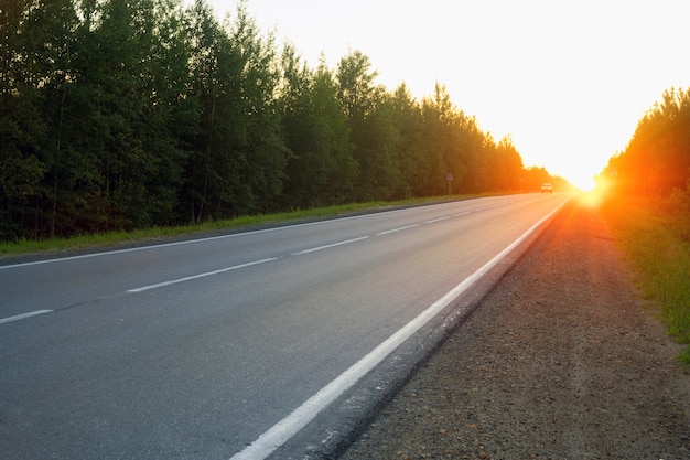 De weg in de avond bij zonsondergang.