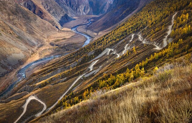 De weg is rotsachtig langs de berghelling die afdaalt in de bergrivier