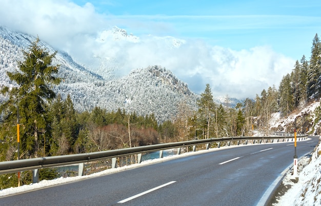 De weg langs de rivier en besneeuwde berghellingen (Oostenrijk, Tirol).