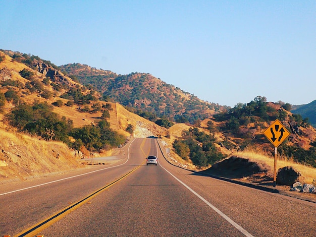 Foto de weg leidt naar de bergen tegen een heldere lucht.