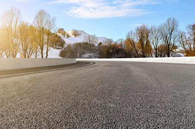 De wegvierkant van het asfalt en rivierheuvel onder de blauwe hemel