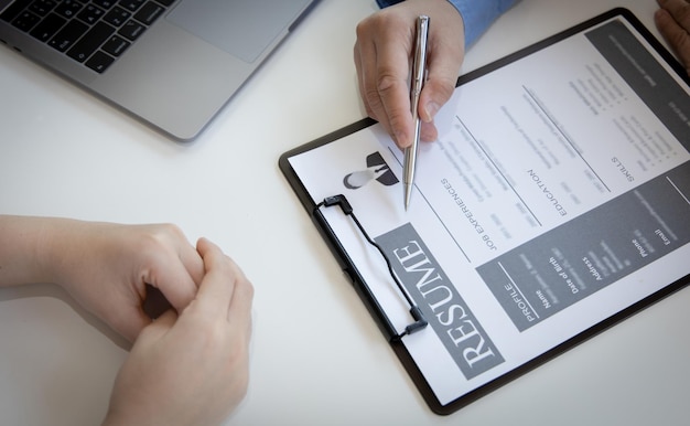 Foto de werkgever of de selectiecommissie leest het cv en de competentie achtergrond van de kandidaten