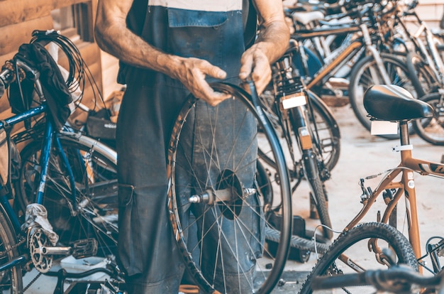 De werkmens in de fietsworkshop bereidt wiel voor de fiets voor
