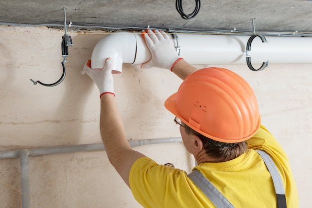 De werknemer die een ventilatiesysteem in het appartement installeert