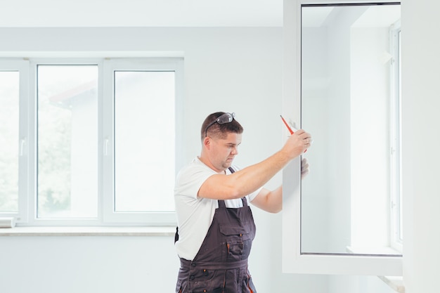 De werknemer past het raam in het appartement van het huis na reparatie aan