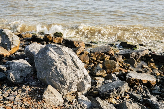 De winderige golven raken de rotsen bij de zee.