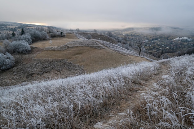 De winter komt eraan Pittoreske pre-zonsopgangscène boven het late herfstberglandschap met rijp op de hellingen van grassenbomen Vreedzame zonlichtstralen van bewolkte hemel Oekraïne Karpaten