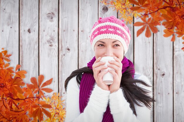 Foto de winterbrunette met koffie tegen het patroon van de herfstbladeren