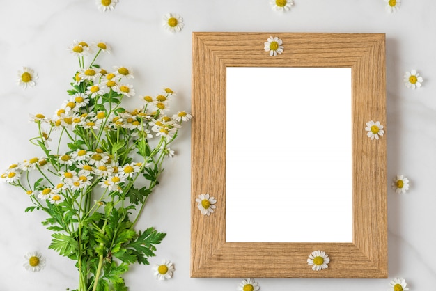 De witte kamille bloeit boeket met leeg fotokader op wit. plat lag. bovenaanzicht