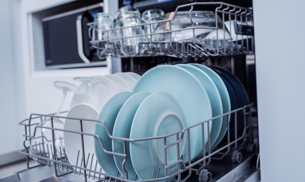 De witte keuken en geopende afwasmachine met schone afwas