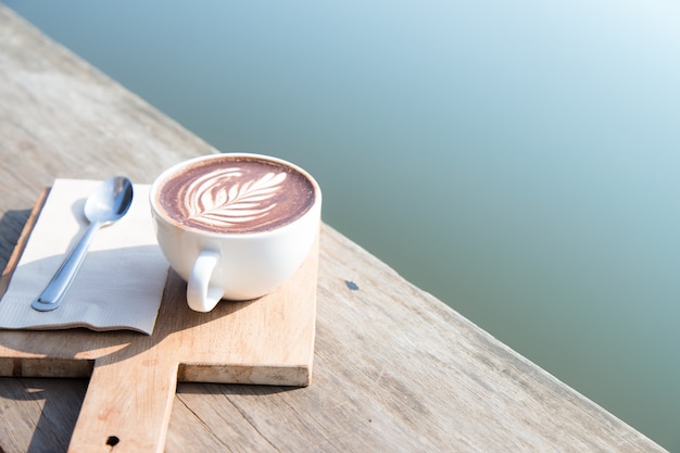 De witte kunst van de koffiekop op houten lijst in koffiewinkel.