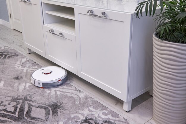 De witte robotstofzuiger reinigt automatisch het grijze tapijt Smart Home-technologie