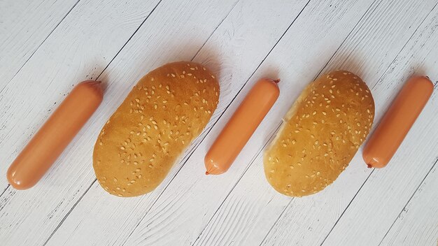 De worsten en de broodjes van de hotdog worden opgesteld in een rij op een houten oppervlakte.