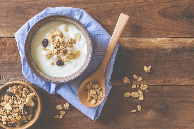 De yoghurt versiert met graangewas in een kom op een oude houten lijst.